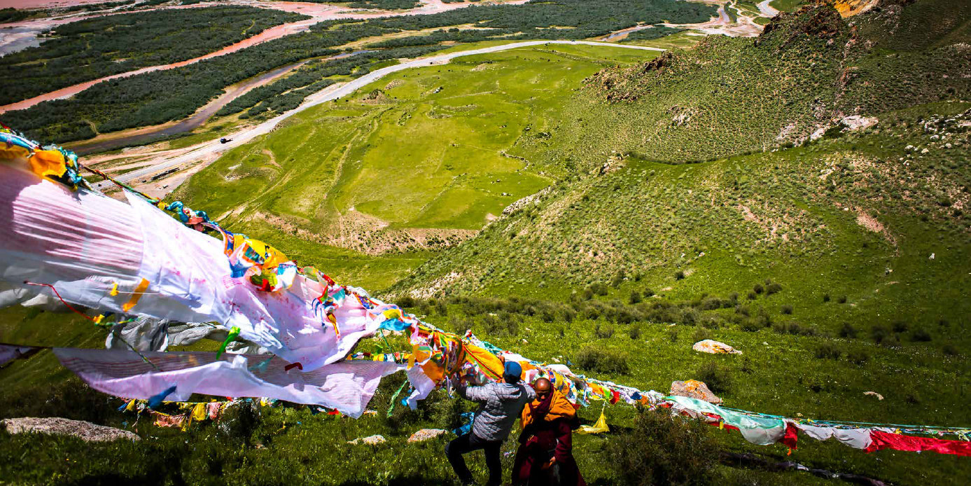 Colorful prayer flags fluttering in the wind against a scenic mountain. landscape. Photographer Diane Barker. Book. Portraits of Tibet. Publisher. Graffeg.